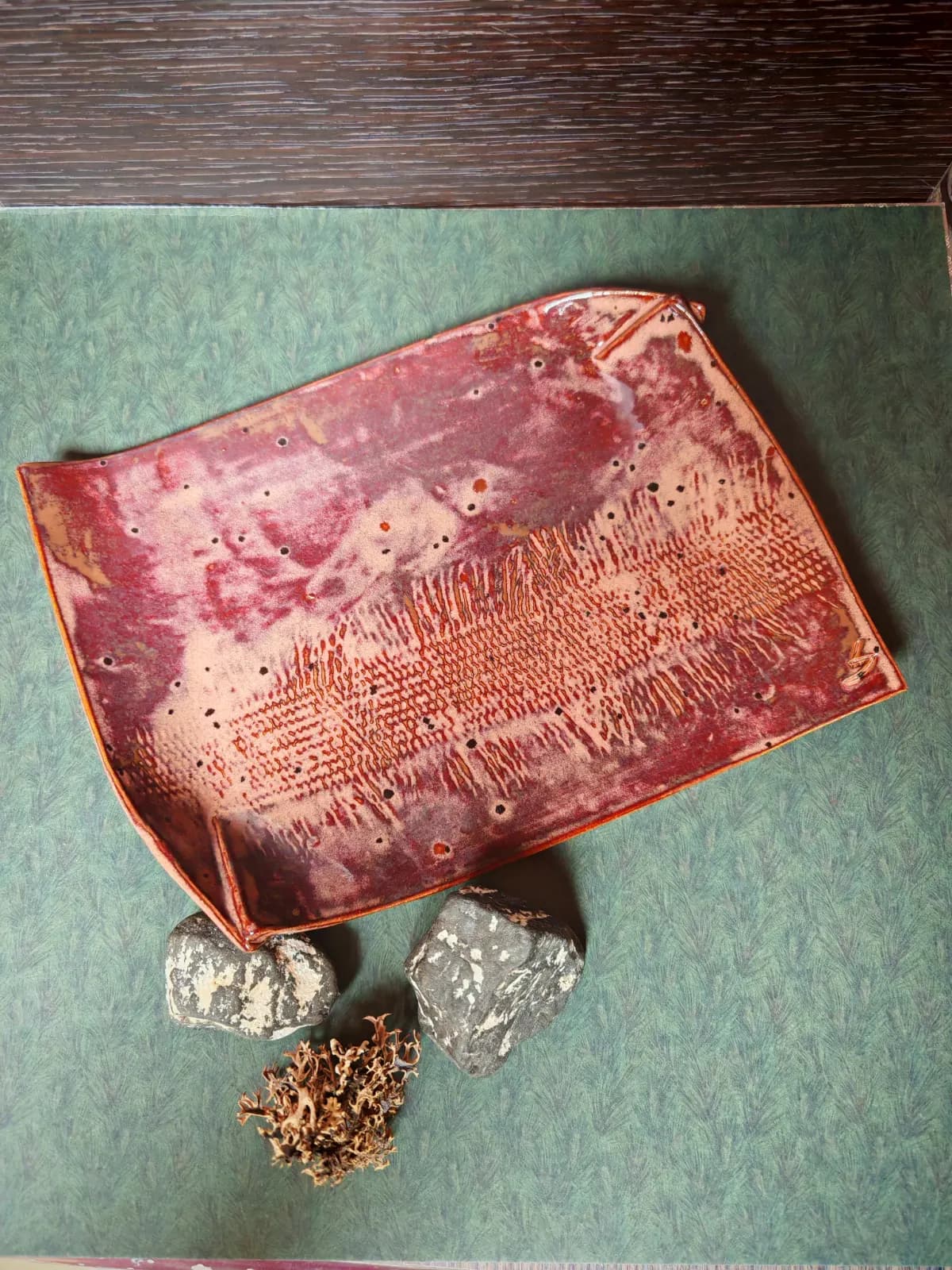 Plat rectangulaire en céramique émaillée aux nuances bordeaux et beige avec motifs texturés.